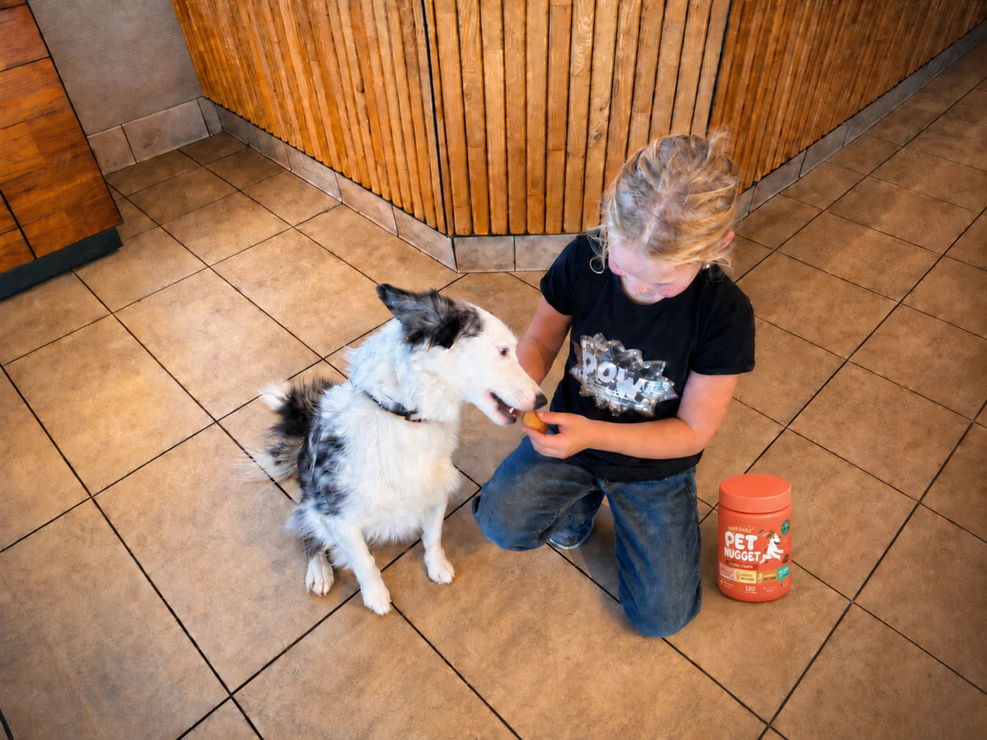 Finley feeding her dog with the Pet Nugget jar beside her